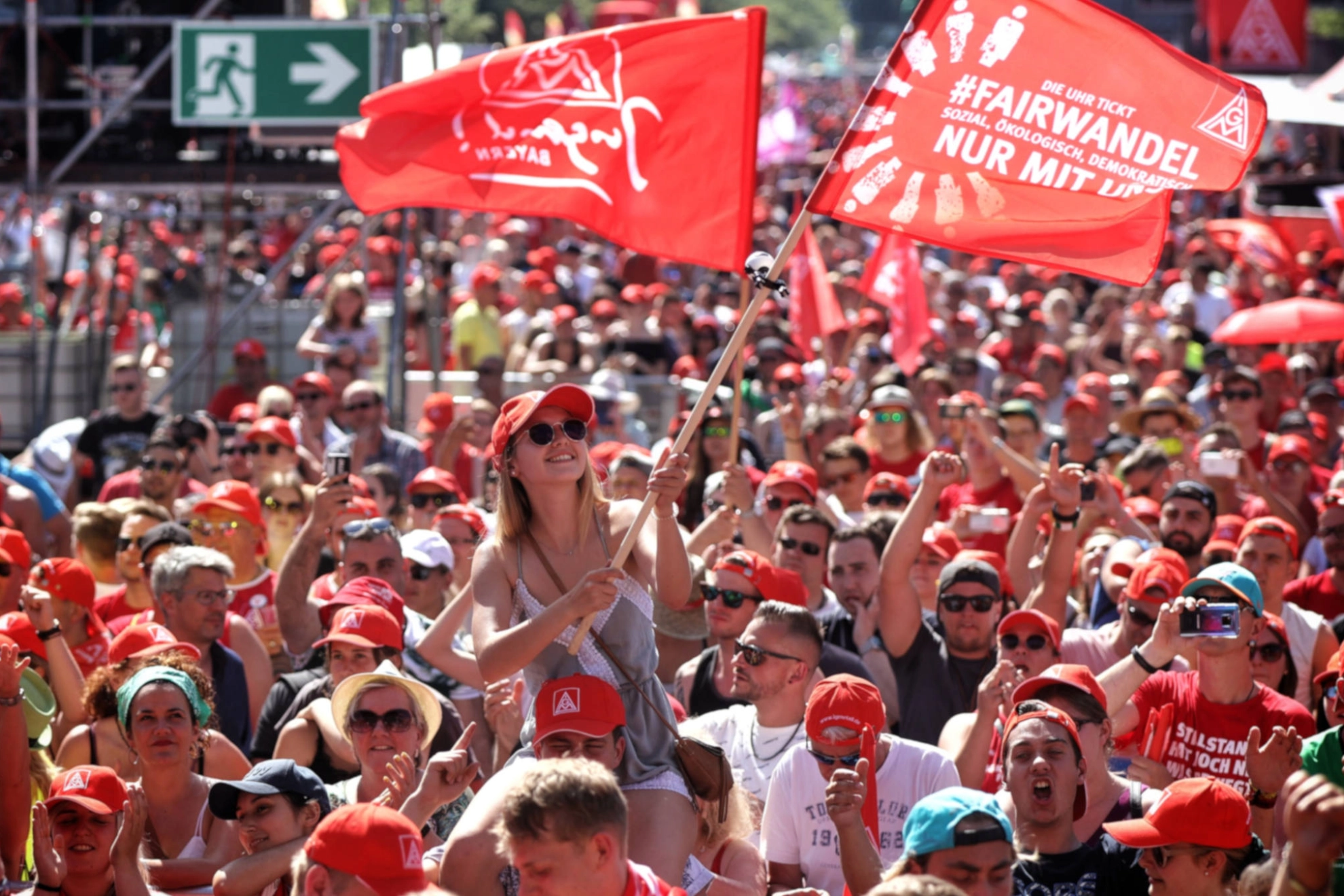 Eine junge Frau schwenkt eine Fahne auf der FairWandel-Kundgebung der IG Metall in Berlin.