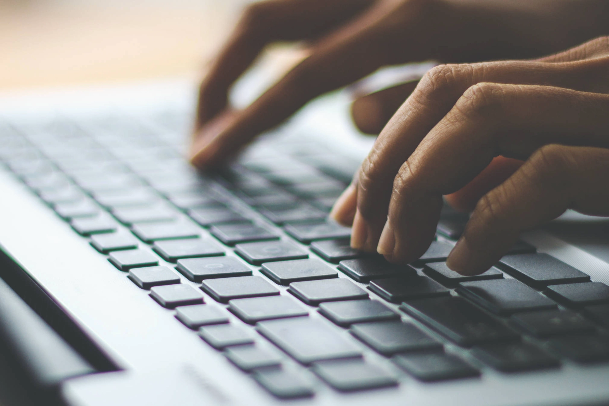 Hände, die auf einer Tastatur tippen.